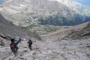 A group of hikers climbs up a long scree field in Rocky Mountain National Park