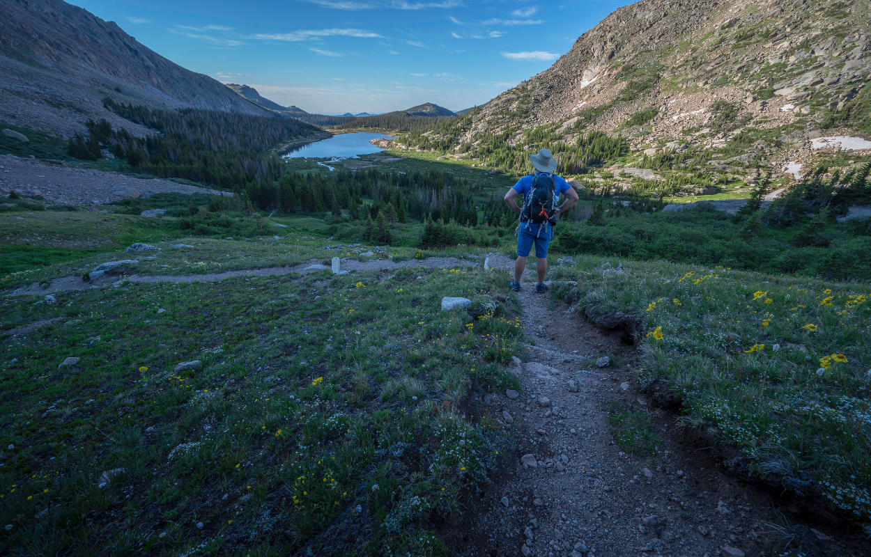 a hiker stands on the trail overlooking lawn lake in Rocky Mountain National Park